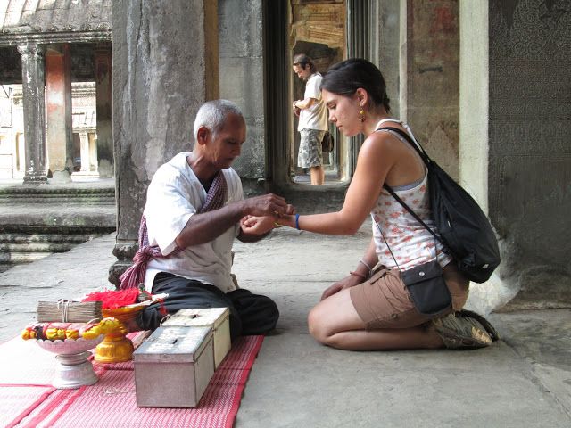 Monje camboyano diciendo una oración mientra pone una pulsera